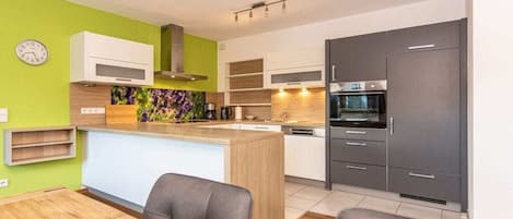 Una cocina moderna con una isla central, electrodomésticos integrados y un comedor con mesa y sillas de madera.