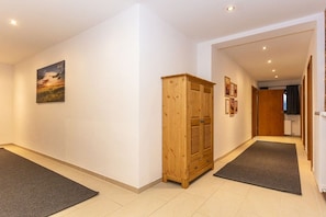 A hallway with a wooden cabinet, a rug, and a painting on the wall. - Holiday apartment in Lofer with swimming pool (Lofer)