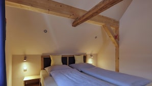 Ein Schlafzimmer mit zwei Betten, Holzbalken und Wandleuchten.