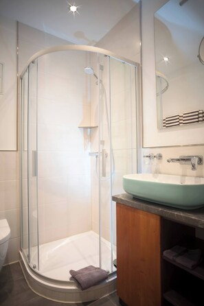 A modern bathroom with a glass-enclosed shower, a sink with a marble countertop, and a mirror above the sink. - Maisonette Apartment The Haystack AD1716 (Marktheidenfeld)