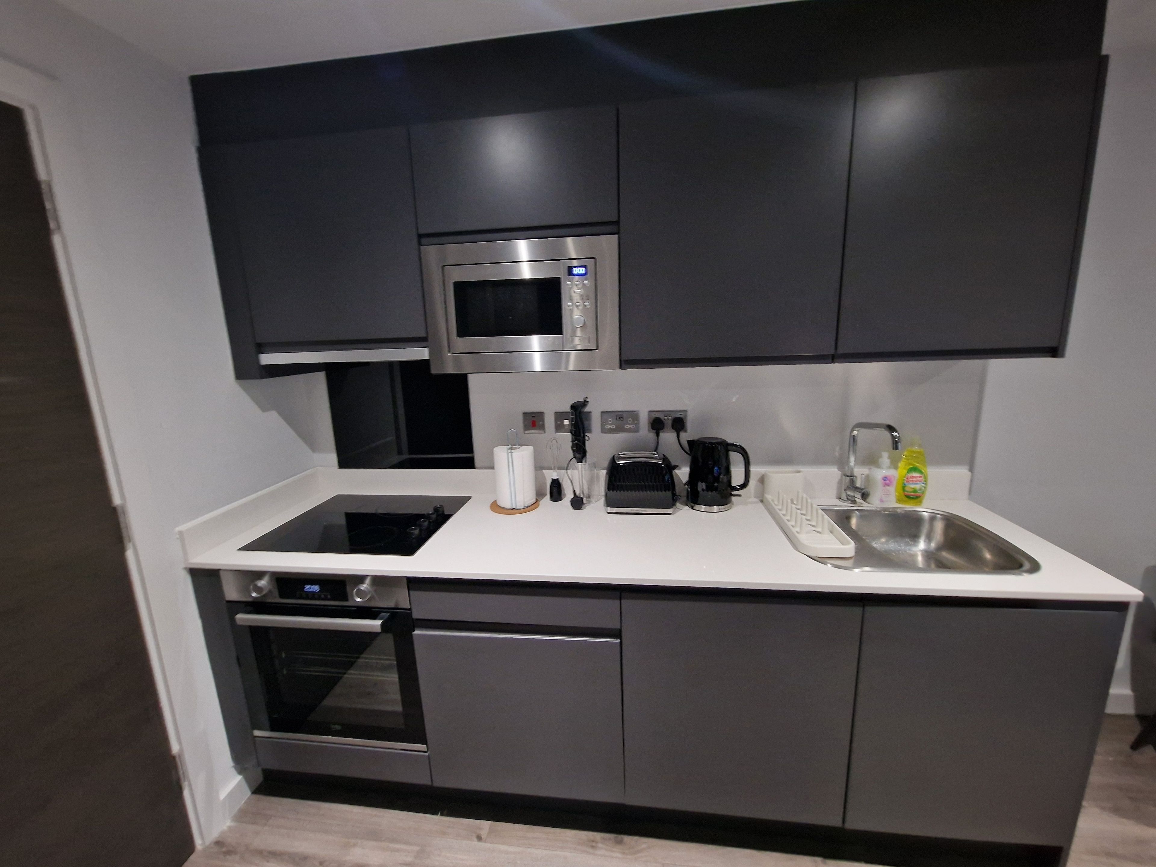 A modern kitchen with a built-in microwave, a coffee maker, and a sink.