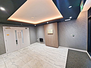 Eine moderne Lobby mit einem geometrischen Deckenmuster, einem Empfangstresen und einem Schild mit der Aufschrift 'MILLERS PLACE'.