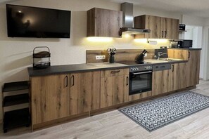 A modern kitchen with wooden cabinets, a built-in oven, and a microwave. - Holiday apartment with 2 bedrooms (Ried im Zillertal)