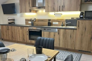 Una cocina moderna con armarios de madera, horno empotrado, lavavajillas y cafetera.