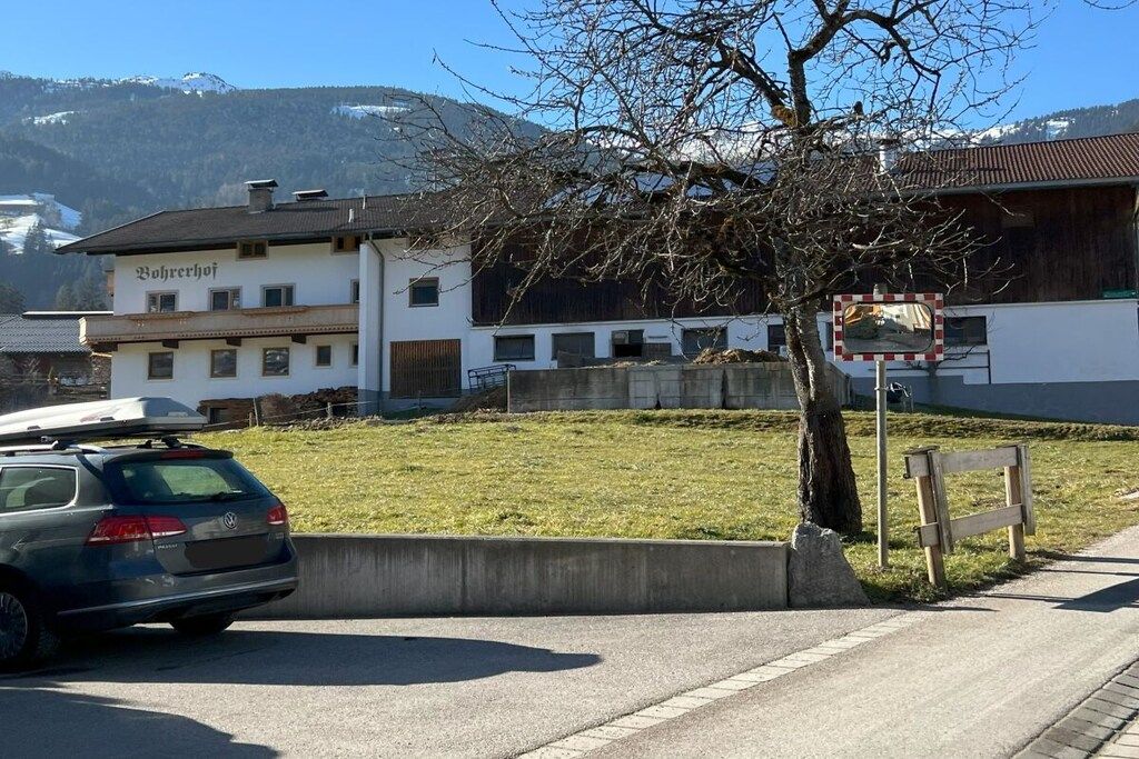 A building with a sign that reads 'Bohrerhof' and a parked car on the side of a road.