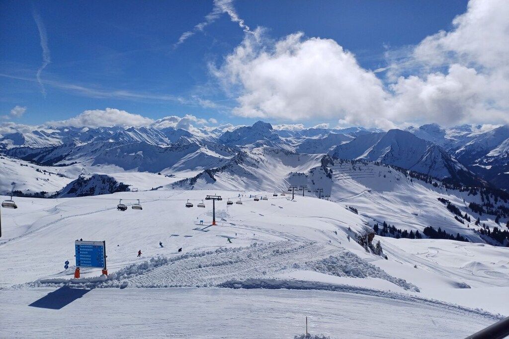 A snow-covered ski slope with a chairlift and a sign indicating ski trails.