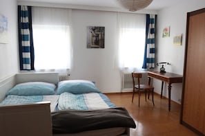 A bedroom with two beds, a desk, a chair, and a radiator. - Holiday apartment with 10 bedrooms (Bad Goisern)