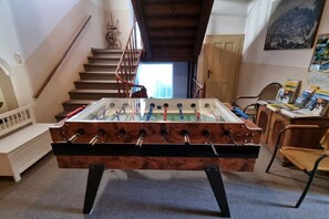 Ein Tischkicker steht in einem Raum mit einer Treppe, einer Tür und einem Stuhl.