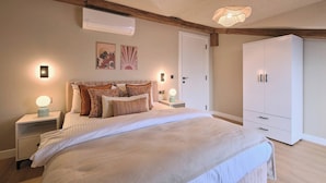 Ein Schlafzimmer mit Bett, Nachttischen, einem Kleiderschrank und Wandleuchten.