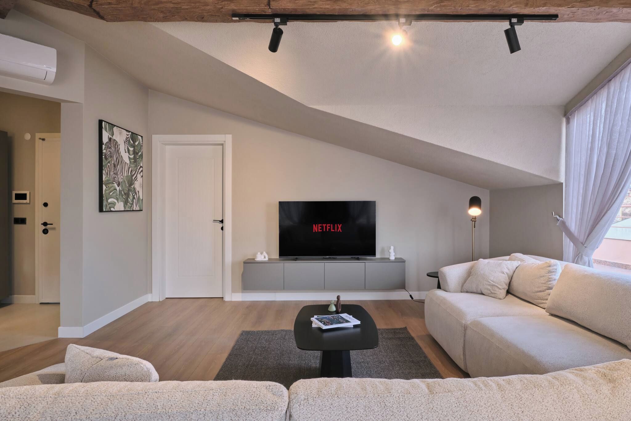Een moderne woonkamer met een flatscreen televisie, een bank, een salontafel en een lamp.