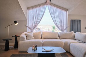 A modern living room with a sectional sofa, a coffee table, a floor lamp, and a view through sheer curtains. - Carlsen, GOAT, Unique, Full City View Terrace (Kadıköy)
