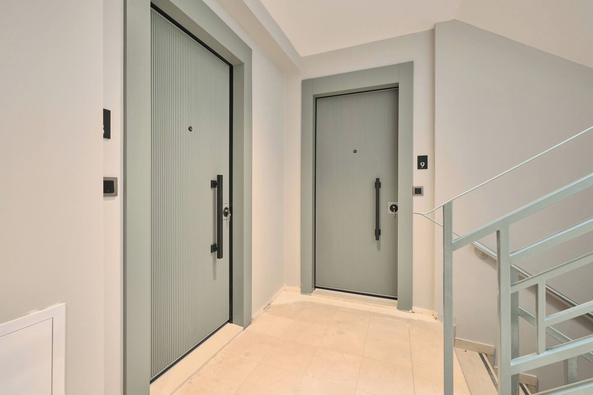 A hallway with two doors, a staircase, and a tiled floor.