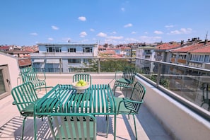 A rooftop terrace with green metal chairs and a table, overlooking a cityscape with buildings and a clear sky. - Classy Duplex, Terrace, 3BR (Kadıköy)