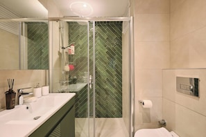 A modern bathroom with a glass-enclosed shower, a large mirror, and a white sink with a soap dispenser. - Classy Duplex, Terrace, 3BR (Kadıköy)
