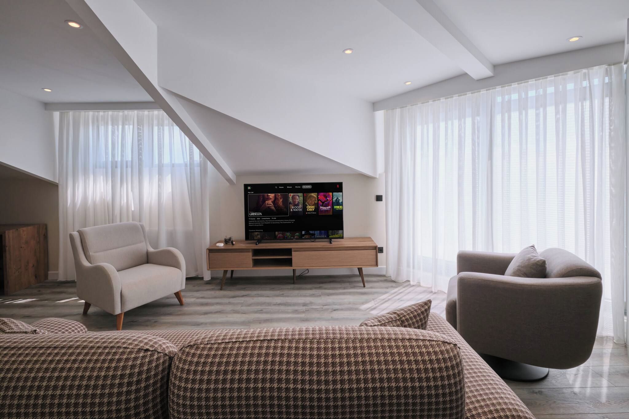 A modern living room with a flat-screen TV, two sofas, and a wooden console table.