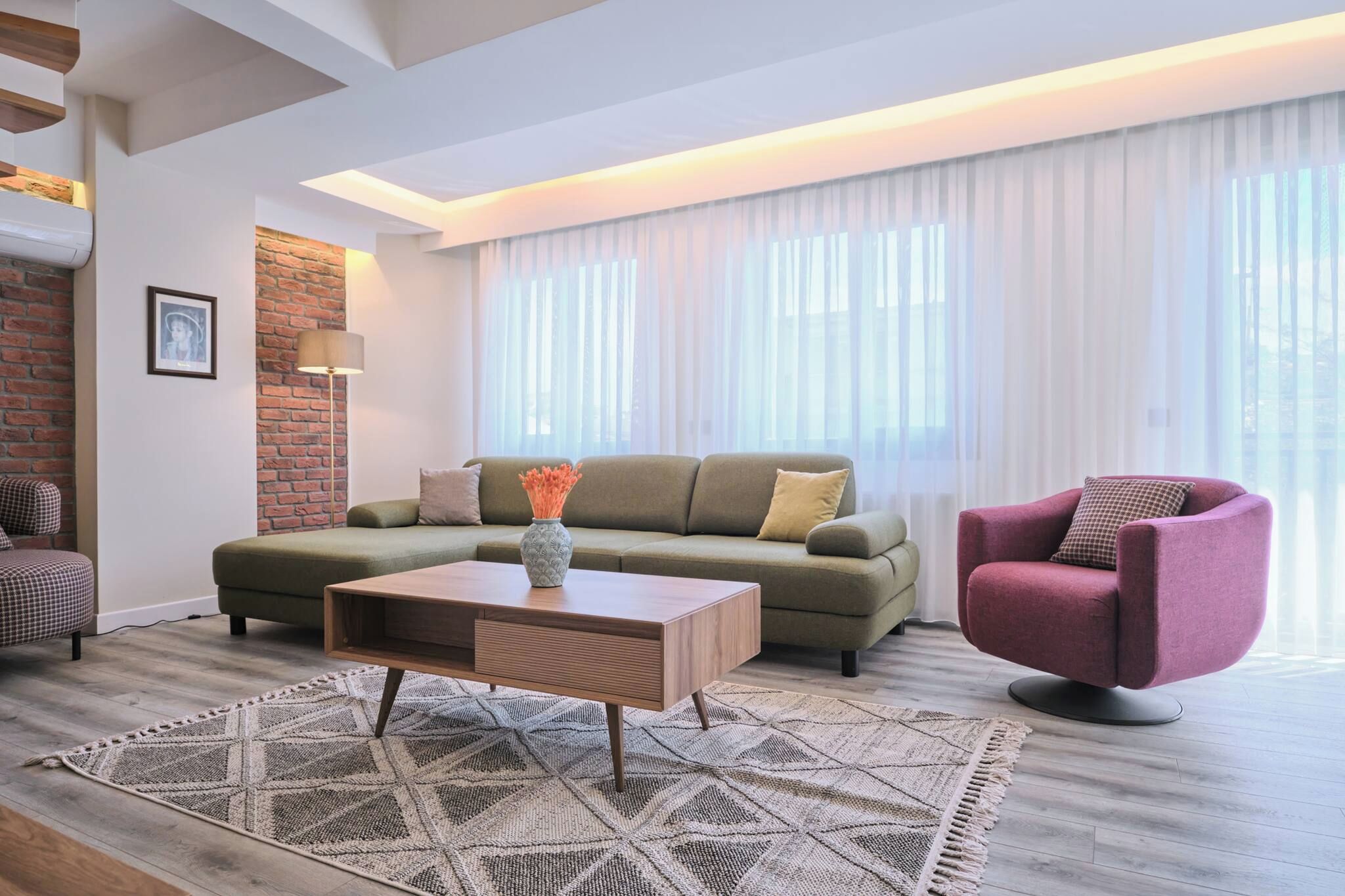 Ein modernes Wohnzimmer mit einer Couch, einem Sessel, einem Couchtisch und einem Teppich.