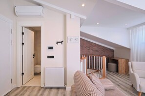 A modern living room with a sofa, a fireplace, and a staircase leading to an upper level. - Classy Duplex, Terrace, 3BR (Kadıköy)