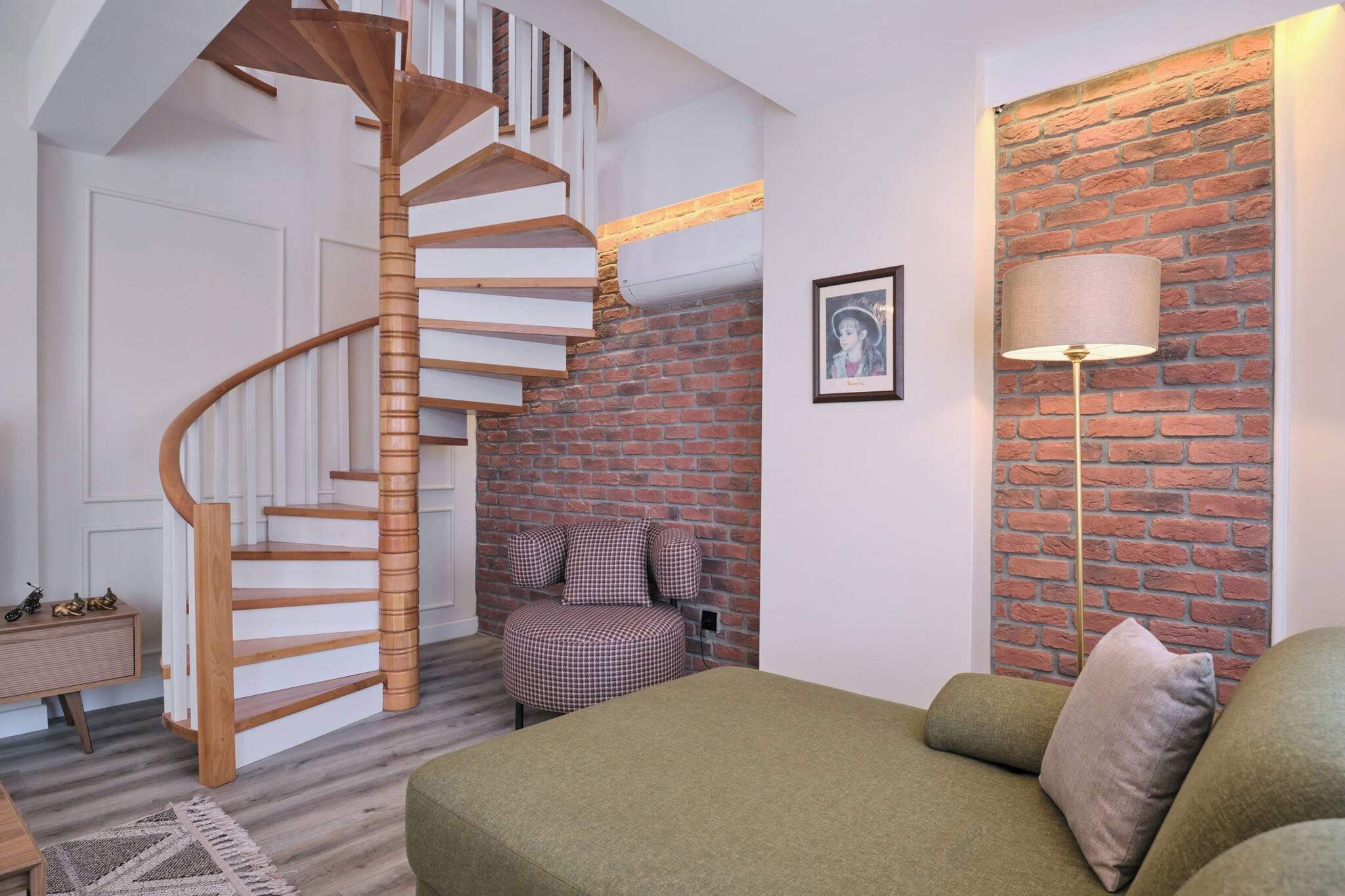 A modern interior with a spiral staircase, a brick wall, a sofa, and a lamp.