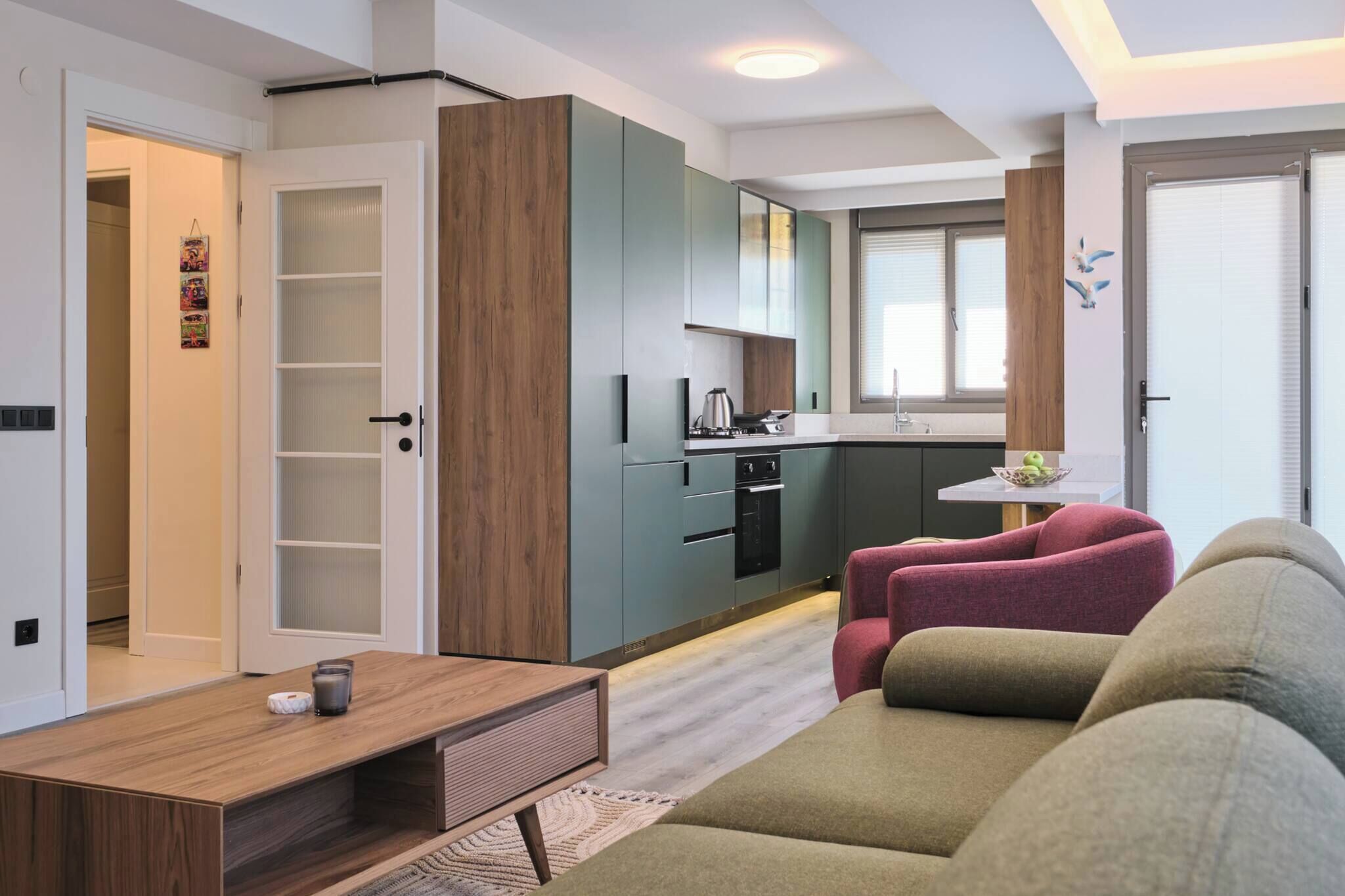 Ein modernes Apartment mit Küchenzeile, einem Sofa, einem Couchtisch und einer Tür zu einem weiteren Raum.