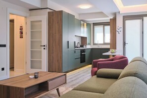 Ein modernes Apartment mit Küchenzeile, einem Sofa, einem Couchtisch und einer Tür zu einem weiteren Raum.