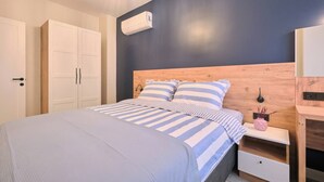 A bedroom with a bed, bedside tables, a wardrobe, and an air conditioning unit. - Cassiopeia, 2BR, Sea View Balcony Best Loc (Kadıköy)