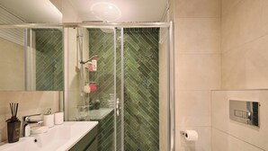 A modern bathroom with a glass-enclosed shower, a large mirror, and a white sink with a soap dispenser. - Cassiopeia, 2BR, Sea View Balcony Best Loc (Kadıköy)