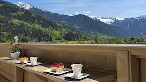 A wooden deck with a table set for a meal, overlooking a mountainous landscape. - Holiday apartment with 2 bedrooms (Hippach)