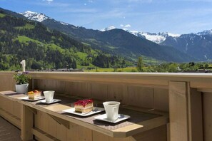 A wooden deck with a table set for a meal, overlooking a mountainous landscape. - Holiday apartment with 2 bedrooms (Hippach)