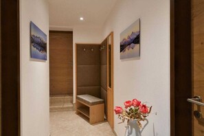 Un couloir avec un banc en bois, un espace douche et un vase rempli de fleurs.