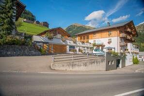 Um hotel com fachada de madeira, um letreiro de restaurante visível e montanhas ao fundo.