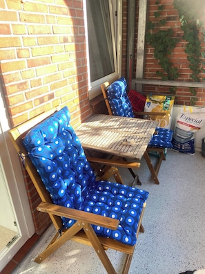 A patio area with a wooden table and two blue polka-dotted chairs.