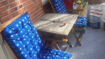 A patio area with a brick wall, a wooden table, and blue polka-dotted chairs.
