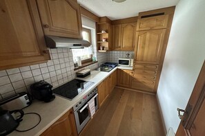 A kitchen with wooden cabinets, a microwave, a stove, and a toaster. - Erharter Country House (Kitzbühel)