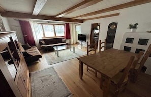 A spacious living area with a wooden dining table, sofas, and a kitchen in the background. - Erharter Country House (Kitzbühel)