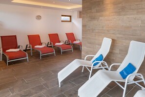 A room with four red chairs and four white chairs arranged in pairs, a clock on the wall, and a wooden floor. - Top 9 for 2-3 people / 1st floor (Schröcken)