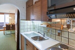 A compact kitchen with a stainless steel sink, wooden cabinets, and a tiled backsplash. - Top 9 for 2-3 people / 1st floor (Schröcken)
