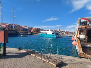 Ein Hafen mit vertäuten Booten, einer hölzernen Pier und Gebäuden im Hintergrund.