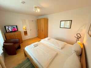 Une chambre d’hôtel équipée d’un lit, d’une télévision, d’une armoire et d’un miroir.