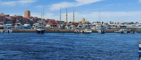 A marina with boats docked, a mosque with two minarets, and a dome in the background.