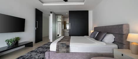 A modern bedroom with a bed, bedside tables, a TV, and a ceiling fan.
