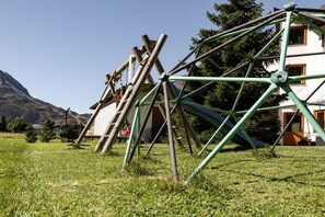 A large metal structure, possibly a windmill, in a grassy field with a building in the background. - Apart Zimalis Galtür Ischgl 3-5 Per. (Galtür)