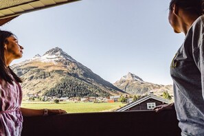 Blick aus einem Fenster auf eine Berglandschaft, im Vordergrund ein kleines Gebäude.