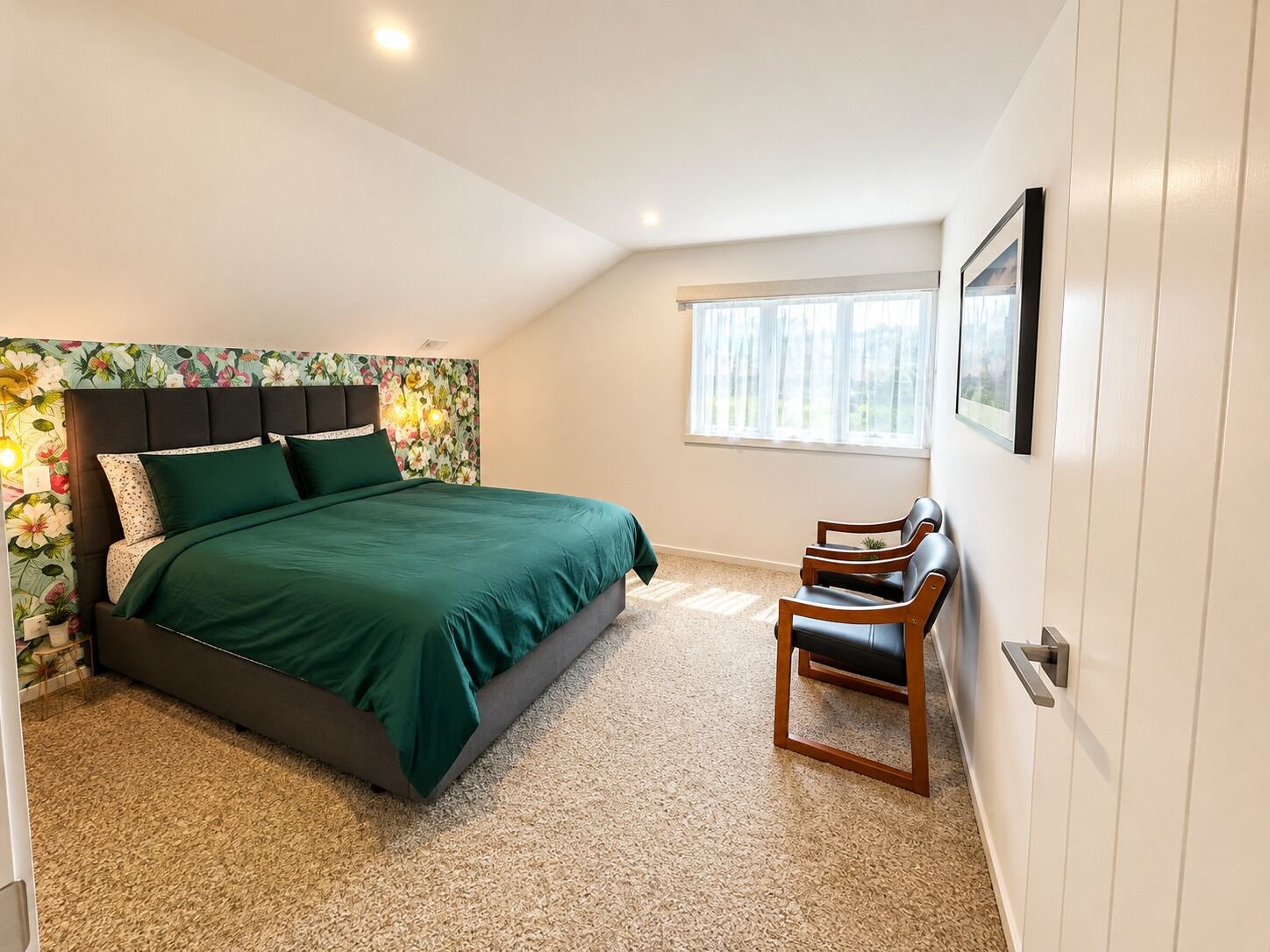 A bedroom with a bed, a window, a chair, and a wall-mounted picture.