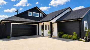 A modern two-story house with a black exterior, a garage, and a well-maintained front yard.