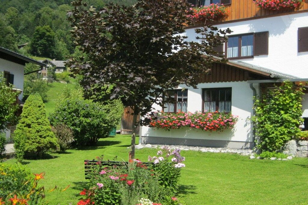 A traditional chalet with a well-maintained garden, wooden shutters, and flower boxes.