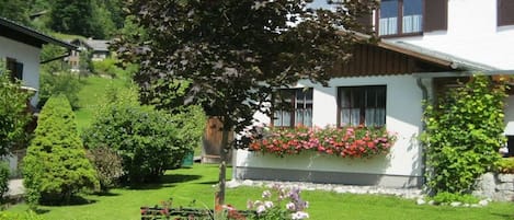 A traditional chalet with a well-maintained garden, wooden shutters, and flower boxes.