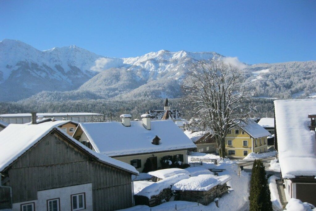 Ein verschneites Dorf mit traditionellen Häusern und einer Bergkulisse.