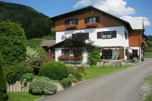 A two-story house with a sloped roof, wooden exterior, and flower boxes on the upper floor. - Musler on the ground floor (Bad Goisern am Hallstättersee)