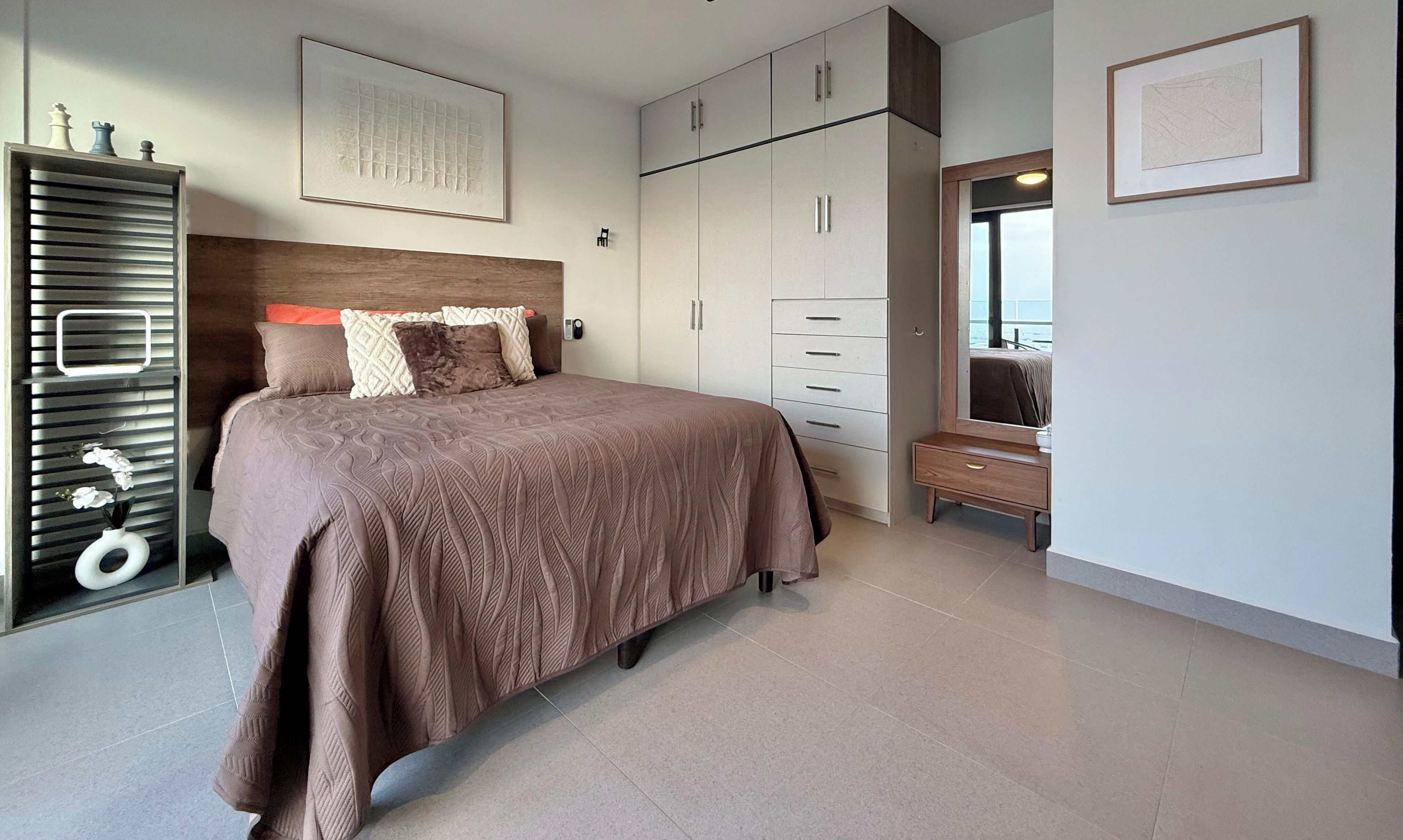 A bedroom with a bed, a dresser, a mirror, and a wardrobe.