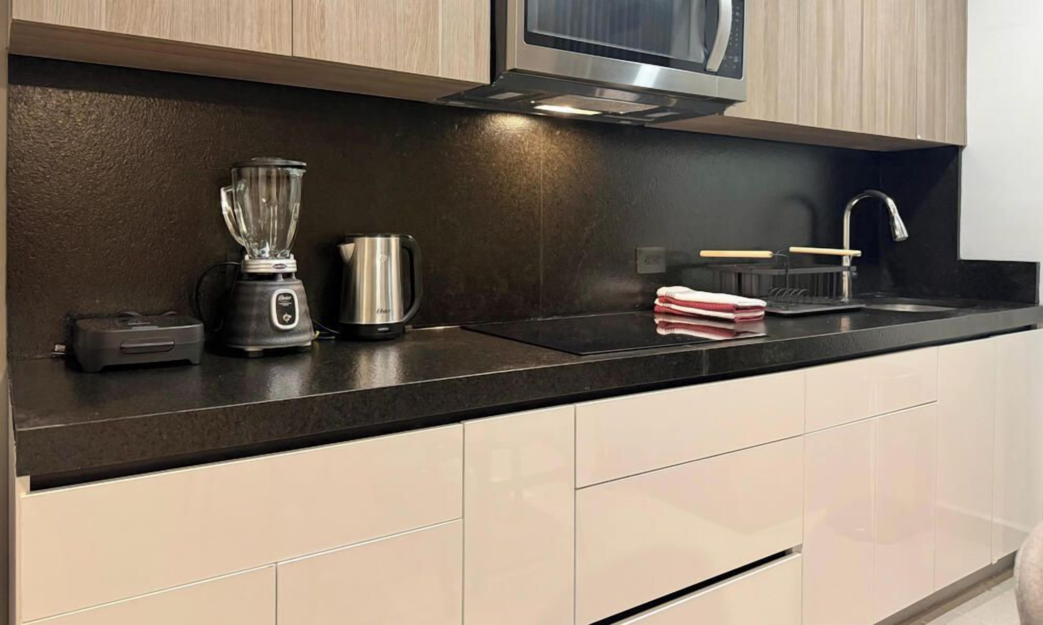 A modern kitchen with a black countertop, stainless steel appliances, and light-colored cabinetry.